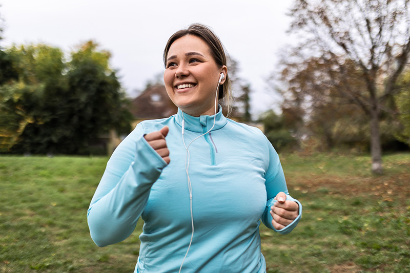 smiling woman jogging with headphones